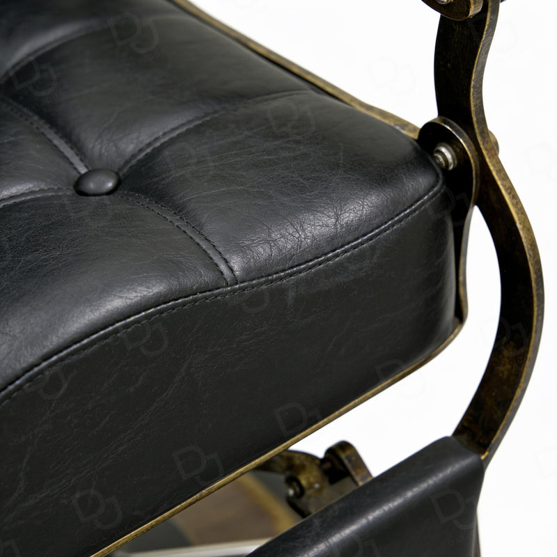 black vintage-style barber chair with quilted padded backrest, adjustable headrest, gold-tone details and footrest
